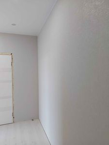 На стенах аккуратно наклеены светлые обои, создающие ровное и гладкое покрытие. Завершенная работа придает помещению свежий и современный вид, гармонично сочетается с интерьером.