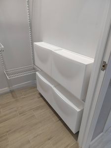 Установлены белые настенные ящики в два ряда на светлой стене. Полки закреплены ровно, обеспечивая надежное хранение. Завершенный монтаж гармонично вписывается в интерьер помещения.