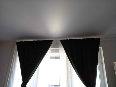 Карниз надежно закреплен на стене, шторы аккуратно развешаны, обеспечивая эстетичный вид и функциональность. Все элементы конструкции установлены ровно и прочно.