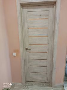 Изображение демонстрирует установленную складную дверь в интерьере. Конструкция закреплена в проеме, оснащена ручкой и петлями. Завершена отделка, обеспечивающая плавное функционирование.