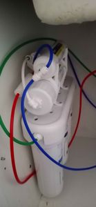 Установлено оборудование для очистки воды под раковиной. Подключены трубки разных цветов, обеспечивающие подачу и отвод жидкости. Все элементы надежно закреплены, система готова к эксплуатации.