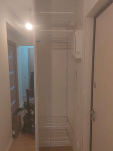 Установлены металлические полки в нише возле двери, обеспечивая дополнительное место для хранения. Конструкция надежно закреплена на стене, создавая удобное решение для организа ции пространства.