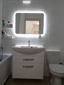 Установлено зеркало с подсветкой, закреплён умывальник с тумбой, подключён смеситель, отрегулирована сантехника, обновлены полки для хранения.