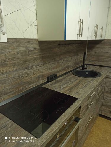 Установлены шкафы, закреплены ручки, смонтирована столешница, подключена варочная панель, врезана мойка, подключен смеситель. Завершена отделка стен фартуком.