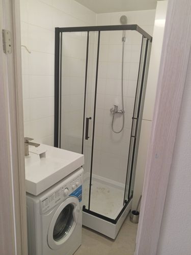 Ванная комната обновлена: смонтирована душевая кабина с прозрачными стенками и черными рамами, подключен смеситель и лейка, обеспечена герметичность и устойчивость конструкции.