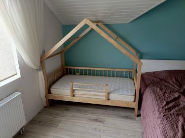 Собрана деревянная кровать с каркасом в виде домика, установлены рейки и матрас. Конструкция надежно закреплена, все элементы тщательно подогнаны для безопасного использования.