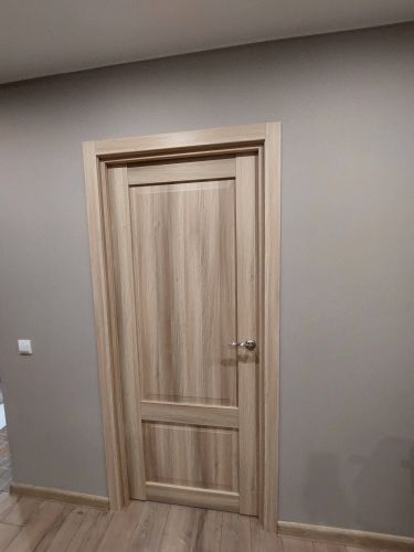 Установлена новая деревянная дверь с ручкой и петлями. Проведена регулировка полотна, закреплён наличник. Проверена плавность открывания и закрывания. Завершена отделка проёма.