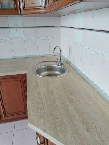 Установлена новая столешница из ДСП, вырезано отверстие для мойки, закреплены все элементы, обработаны стыки герметиком, обеспечена надежная фиксация и аккуратное прилегание к стене.