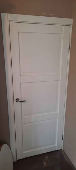 Установлена новая дверь, уменьшен проем, добавлены наличники, обновлена фурнитура, покрашены поверхности, улучшена изоляция, выровнены стены, завершена отделка.