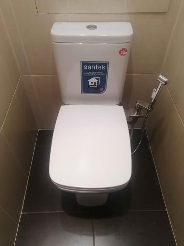 Изображен установленный унитаз в санузле с плиточным полом и стенами. Сантехническое оборудование подключено, все элементы на месте, работа завершена.