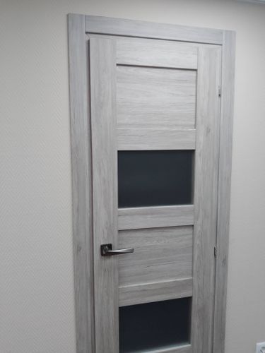 Установлена светлая дверь с матовыми стеклянными вставками. Закреплён короб, навешана створка, врезаны петли и ручка. Все элементы выровнены, обеспечено плавное открывание.