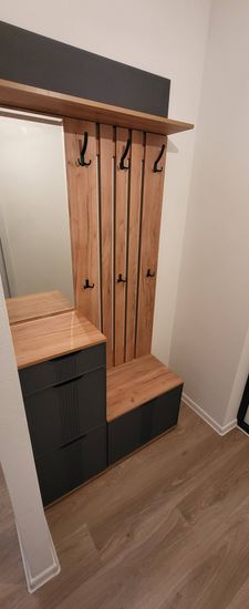 Установлены полки, закреплены крючки, собран шкаф с ящиками, смонтирована скамья, прикреплено зеркало. Все элементы надежно соединены, обеспечивая функциональность и эстетичность.