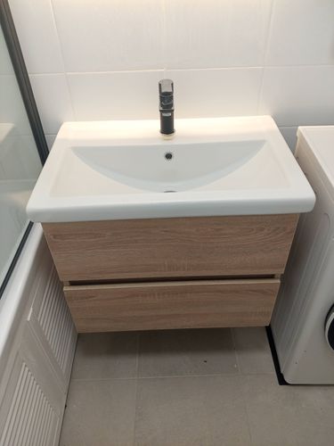 Изображение ванной комнаты с раковиной, установленной на деревянной тумбе. Полотенцесушитель не виден, но предполагается, что он подключен и готов к использованию.