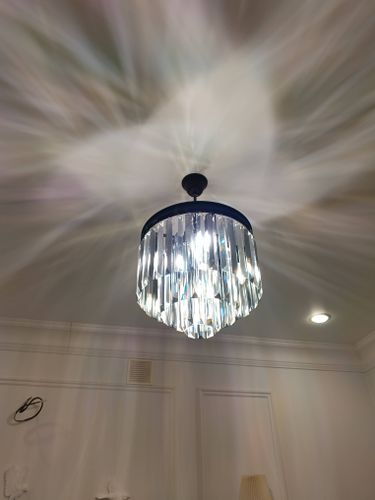 Закреплена люстра на натяжной поверхности, подключены провода, проверена работа освещения. Светильник ровно висит, создавая красивый световой эффект на потолке.