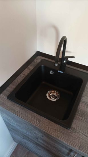 Установлена кухонная мебель, смонтирована столешница из ДСП, врезана мойка, подключен смеситель. Все элементы аккуратно подогнаны и закреплены, обеспечивая функциональность и стиль.