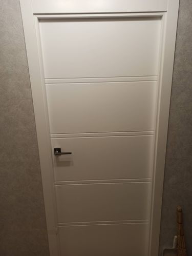 Установлена белая дверь с ручкой, аккуратно закреплена в проеме. Проведены работы по монтажу, выравниванию и фиксации. Дверь плавно открывается и закрывается, обеспечивая комфорт.