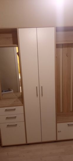 Собрана мебель: шкаф с дверцами, ящики с ручками, зеркало, вешалки для одежды. Установлены все элементы, обеспечена устойчивость, функциональность и эстетичный вид.