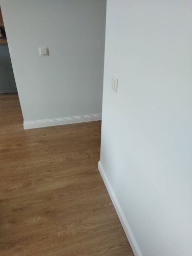 Установлен скрытый плинтус, аккуратно вписанный в стену, создающий плавный переход между полом и стеной. Завершенная работа придает интерьеру современный и элегантный вид.