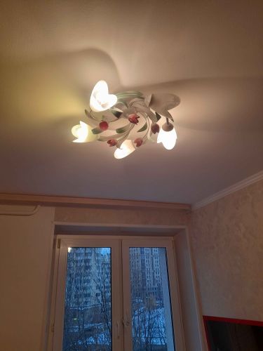 Закреплён стильный светильник с цветочными элементами, подключены провода, проверена работоспособность. Создано уютное освещение, гармонирующее с интерьером комнаты.