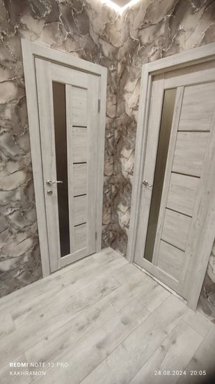 Установлены новые деревянные двери с фурнитурой, включая ручки и замки. Проведена точная подгонка полотна в проем, обеспечена плавная работа механизма. Завершена отделка наличниками.