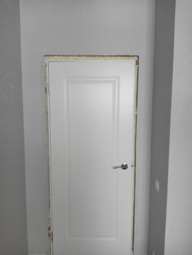 Стены оклеены светлыми обоями, создающими ровную и аккуратную поверхность. Вокруг двери выполнена точная подгонка материала, обеспечивающая чистый и завершённый вид.