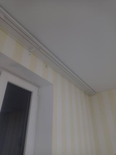 Закреплен профиль на поверхности, установлены крепежи, проверена надежность конструкции. Карниз ровно размещен над оконным проемом, обеспечивая функциональность и эстетичность.