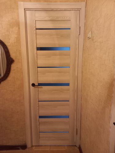 Установлена новая деревянная дверь, закреплены петли, врезан замок, смонтирована ручка, выровнена коробка, выполнена отделка откосов, проверена плавность открывания и закрывания.