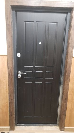 Установлены деревянные доборы вокруг входной двери, обеспечивая завершенный вид и улучшенную изоляцию. Элементы плотно прилегают, создавая гармоничный переход между стеной и дверью.