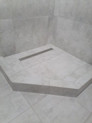 Проведена укладка керамогранита на подготовленную поверхность. Плитка уложена ровно, швы аккуратно обработаны. Завершено оформление душевого поддона с встроенным сливом.