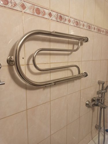 Закреплен новый водяной полотенцесушитель на стене ванной комнаты. Подключены трубы к системе водоснабжения, обеспечена герметичность соединений. Устройство готово к использованию.