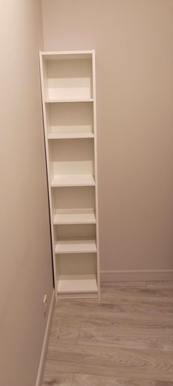 Установлена белая конструкция с пятью полками в углу комнаты. Все элементы аккуратно соединены, обеспечивая устойчивость и функциональность. Полки готовы к использованию.