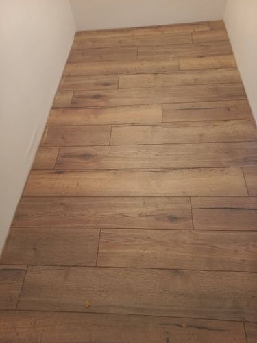 Уложено новое покрытие, ровно и аккуратно, без зазоров. Панели подобраны по цвету и текстуре, создавая гармоничный вид. Работа завершена, пол готов к использованию.