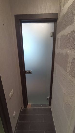 Установлена новая дверь с матовым стеклом, закреплена коробка, врезаны петли, прикреплена ручка, отрегулировано полотно, проверена плавность хода, завершена отделка откосов.