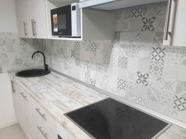 На изображении завершена установка кухонной поверхности: аккуратный распил, подгонка по размерам, монтаж варочной панели и мойки, обеспечивая функциональность и эстетичный вид.