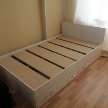 Собрана конструкция с каркасом, закреплено изголовье, установлены ламели. Встроены ящики с ручками, обеспечивающие дополнительное хранение. Работа завершена, мебель готова к использованию.