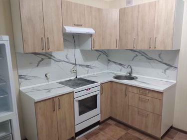 Кухонная поверхность аккуратно подогнана, установлена мойка, плита. Все элементы гармонично сочетаются, создавая единый стиль. Работы завершены, результат впечатляет.