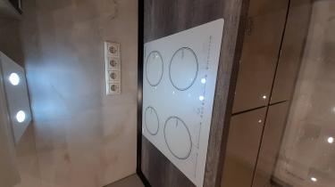 Установлена варочная панель на столешницу из ДСП, подключены розетки, смонтированы шкафы, обеспечено освещение. Завершена интеграция всех элементов, включая бытовую технику.