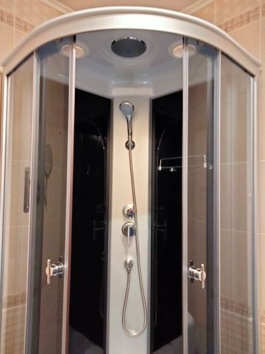 Установлена современная душевая конструкция с прозрачными дверями, смесителем и душевой лейкой. Завершены работы по монтажу, подключению водоснабжения и герметизации.