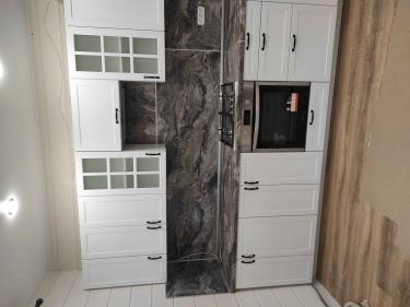 Установлены шкафы, закреплены фасады, смонтирована столешница из камня, подключена варочная панель, вмонтирована духовка, выполнена отделка стен, установлены ручки.