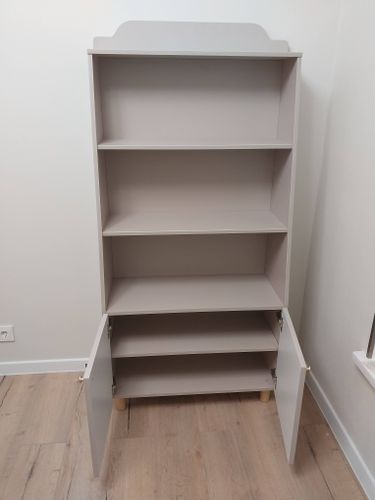 Собран новый стеллаж: установлены полки, закреплены дверцы, выровнена конструкция. Элементы соединены, обеспечена устойчивость. Готов к использованию в интерьере.