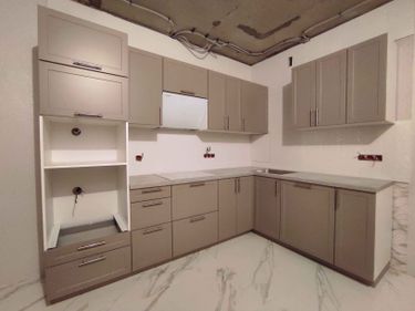 На изображении видно, что выполнена установка кухонной столешницы с точными вырезами под мойку и варочную панель. Поверхность аккуратно подогнана к шкафам, обеспечивая плавный переход.