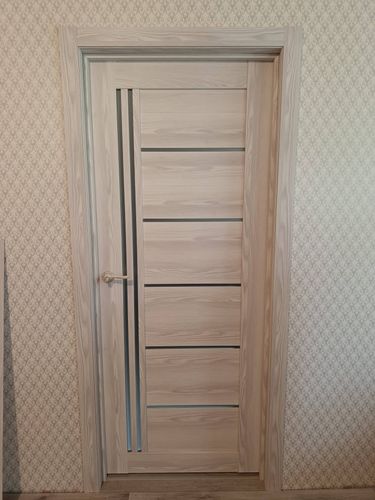 Установлена светлая межкомнатная дверь с вертикальным стеклянным элементом, аккуратно закреплена в проеме, оснащена ручкой и наличниками, гармонично вписывается в интерьер.