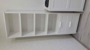 Собран белый комод с двумя выдвижными ящиками и тремя полками. Все детали аккуратно соединены, конструкция устойчива, поверхность гладкая, ручки крепко закреплены.