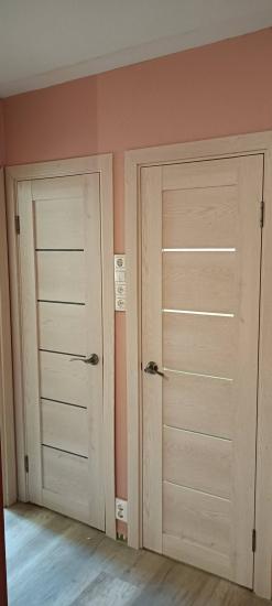 Установлена новая деревянная дверь, закреплены петли, врезан замок, отрегулирована фурнитура, проверена плавность открывания, произведена отделка наличниками, обеспечена надежная фиксация.