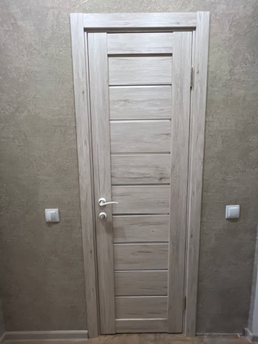 Изображена установленная дверь-гармошка в светлом оттенке, аккуратно закрепленная в проеме. Завершены работы по монтажу, включая фиксацию петель и ручки.