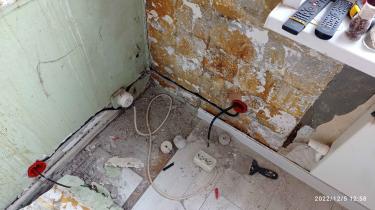 Удаление старого кабеля из стены, освобождение пространства от проводов, подготовка поверхности для дальнейших работ. Видны остатки штукатурки и строительный мусор.