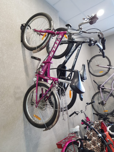 Изображены велосипеды, подвешенные на стене с помощью специальных креплений. Установлены надежные держатели, обеспечивающие безопасное и удобное хранение транспортных средств.