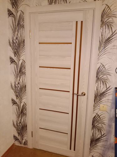 Установлена светлая дверь с вертикальными вставками, смонтирована ручка, закреплены петли, произведена регулировка полотна, обеспечена плавная работа, оформлен проем.