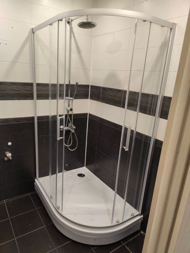 Установлен душевой уголок: закреплены стеклянные панели, поддон, смеситель и лейка. Подключены водопроводные трубы, проверена герметичность соединений. Завершено оформление пространства.