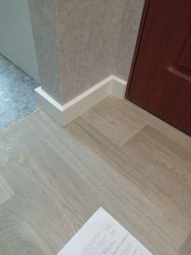 Установлен современный плинтус, аккуратно прилегающий к стене и полу. Завершенный монтаж обеспечивает эстетичный вид и скрывает стыки, создавая плавный переход между поверхностями.